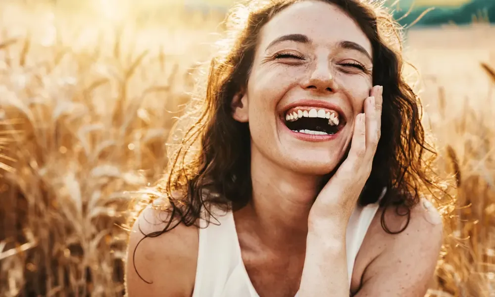 Woman with curly red hair smiling outdoors in natural light, embodying warmth and approachability central to healing work.