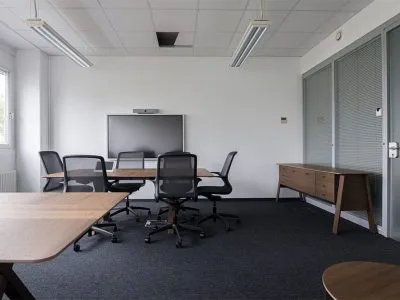 Bright meeting room with ergonomic chairs, a display screen, and glass partition walls.