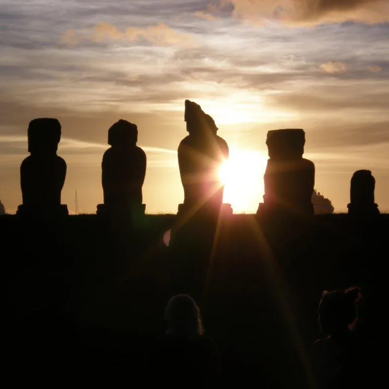 Silhouettes of Easter Island moai statues against a golden sunset sky.