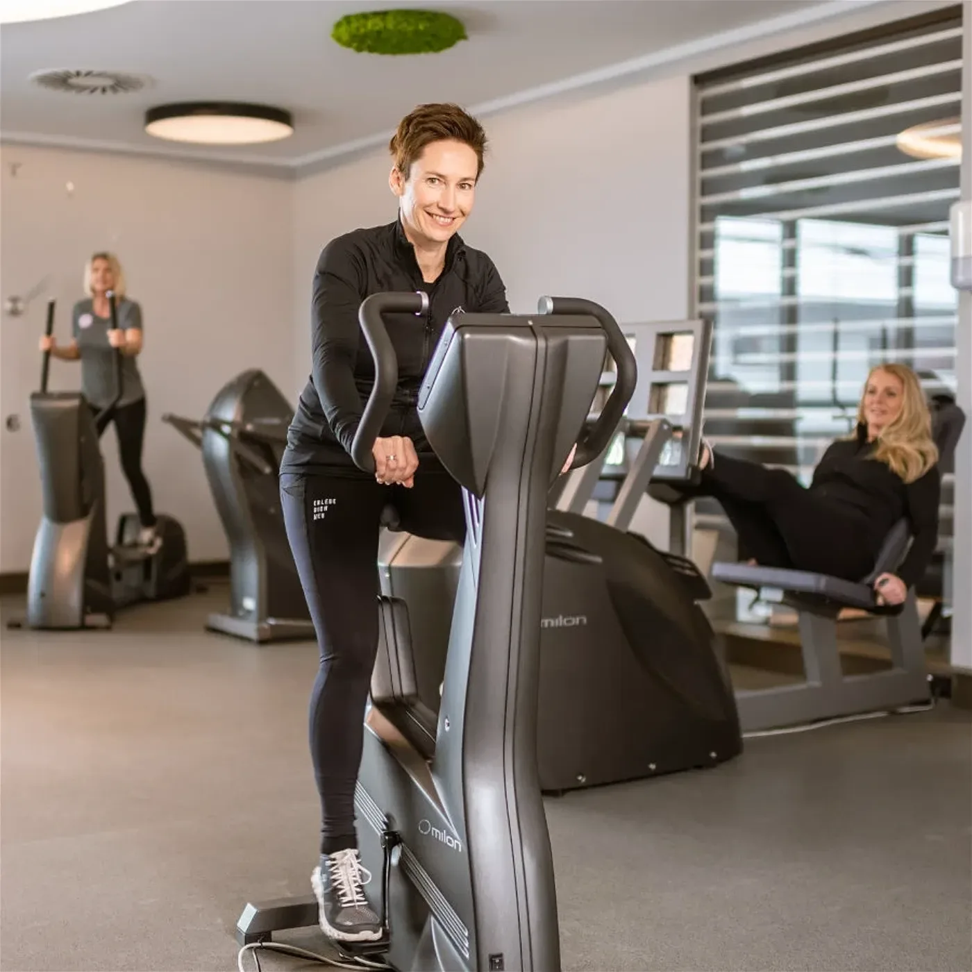 Female trainer guiding client on stability ball with professional, caring presence in modern wellness studio.