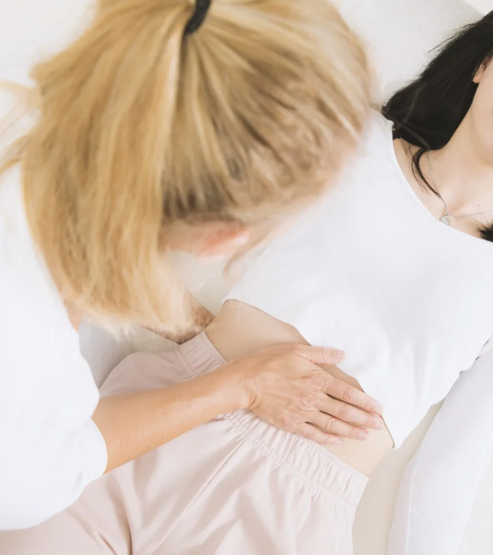 Therapeutin Christiane Gneissl führt eine heilsame Shiatsu-Behandlung durch, wobei sie achtsam die Hände auf dem Rücken einer entspannten Klientin platziert.